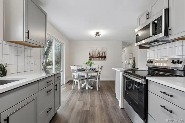a kitchen with stainless steel appliances wooden floor sink stove and cabinets
