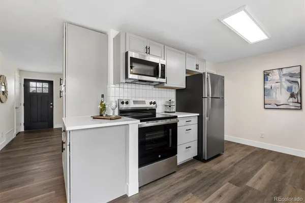 a kitchen with a refrigerator stove and wooden floor