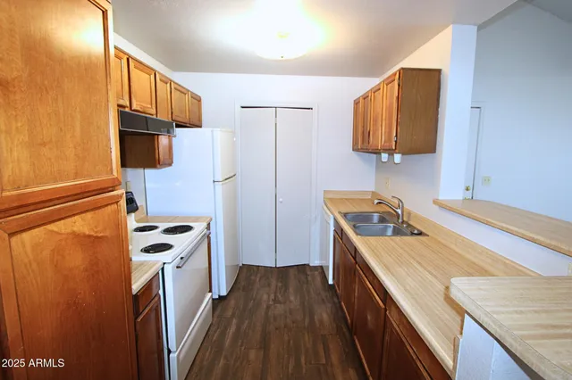 a kitchen with stainless steel appliances granite countertop a refrigerator a stove and a sink with wooden floor