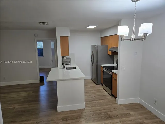 a kitchen with a sink a refrigerator and wooden floor