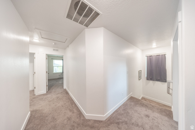 4765 Breezy Patch Road Eagle Mountain, UT 84005 - Photo 15 of 25 Hallway featuring neutral-toned carpet flooring, white painted walls, and an attic access panel