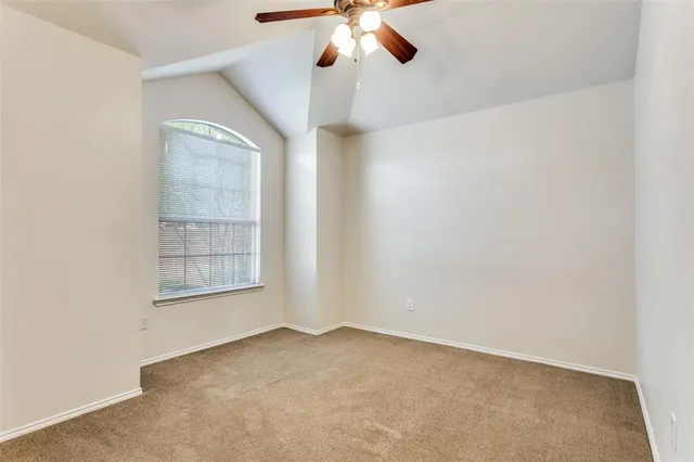 an empty room with ceiling fan and window