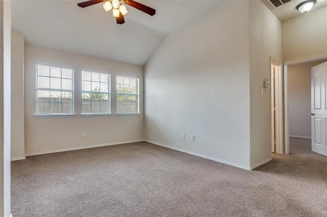 an empty room with chandelier fan and windows