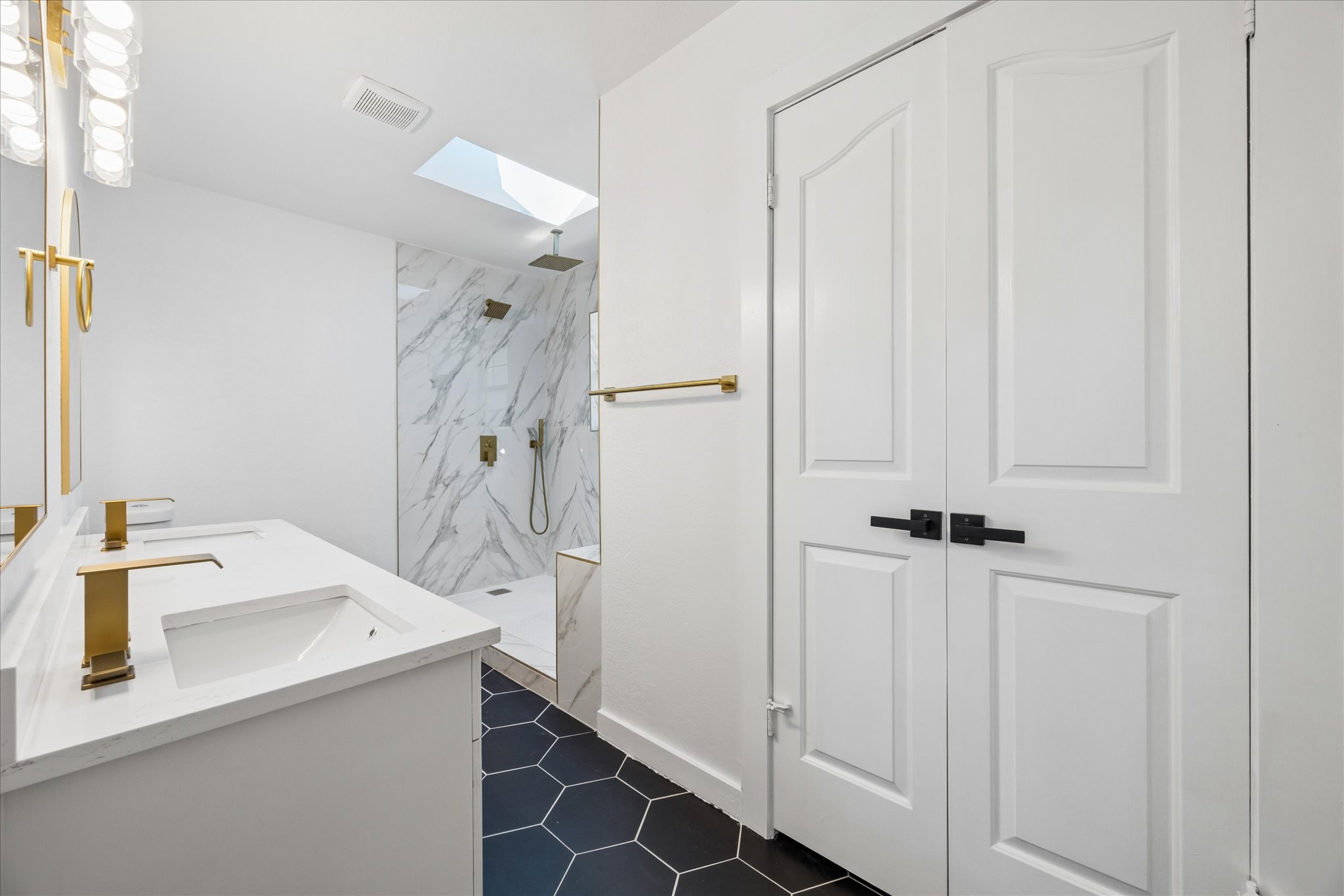 1706 Davis Street Taylor, TX 76574 - Photo 9 of 18 A striking primary bath boasts dual vanities, modern fixtures, and a glass-enclosed shower with a skylight.