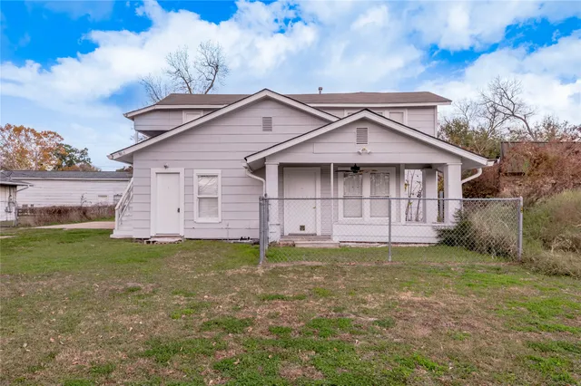 a view of a house with a yard and a large tree