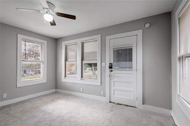 a view of empty room with windows and chandelier fan