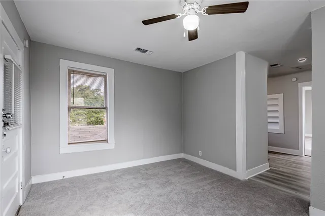 an empty room with windows and fan