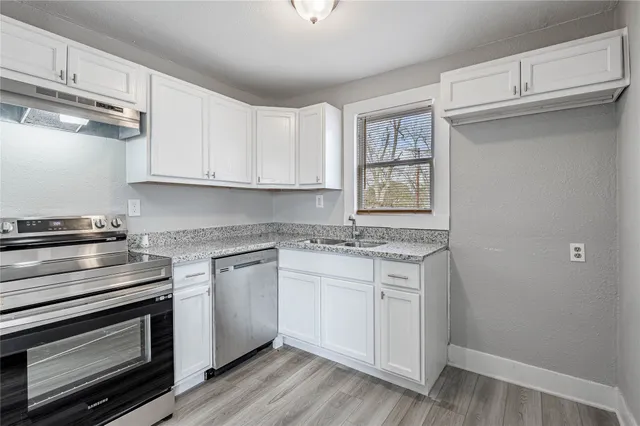 a kitchen with stainless steel appliances granite countertop a stove and white cabinets