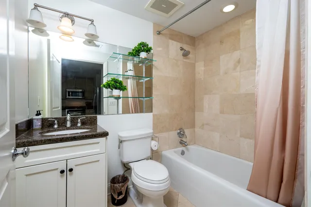 a bathroom with a granite countertop sink a toilet and shower