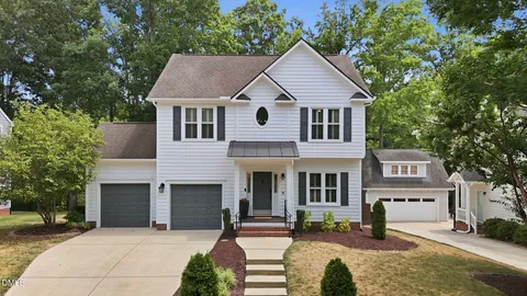 a front view of a house with a garden and trees