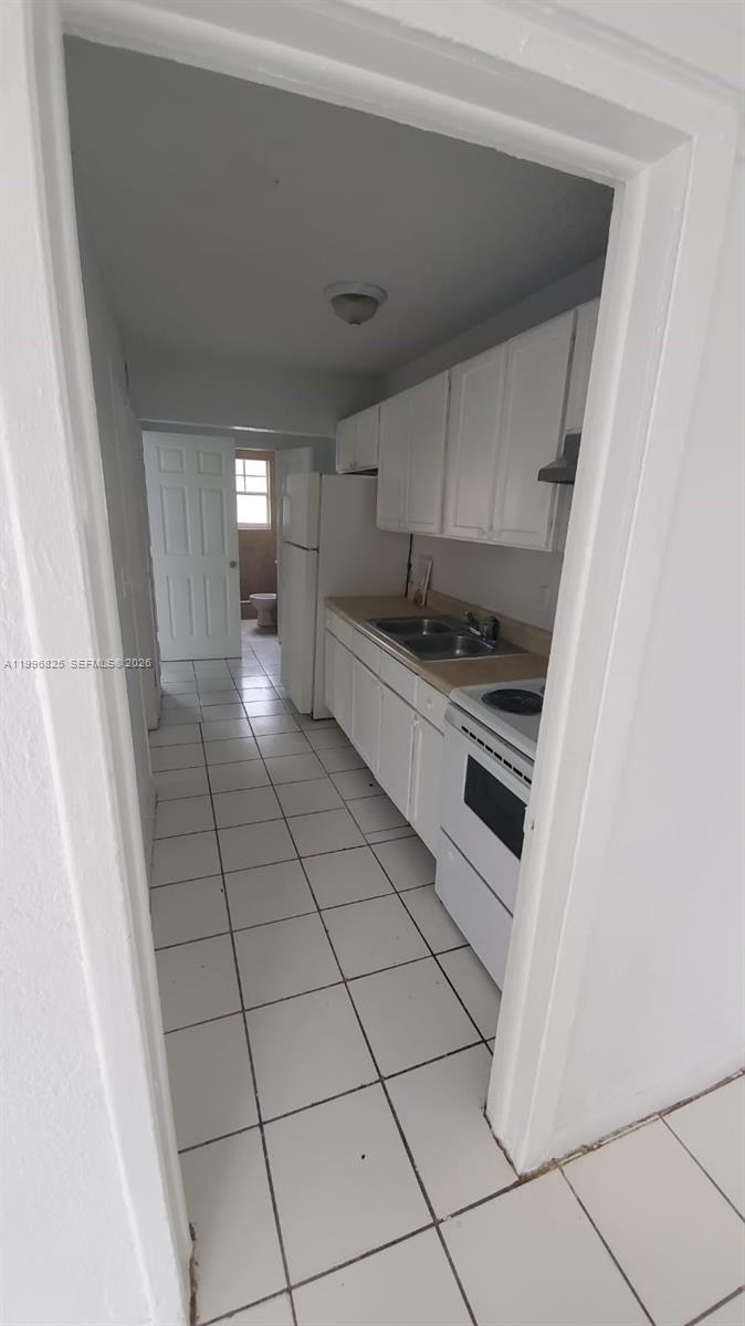 2980 Northwest 91st Street, Unit 1 Miami, FL 33147 - Photo 4 of 9 a kitchen with granite countertop white cabinets and white appliances