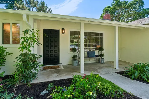 a view of a white house with a yard and potted plants