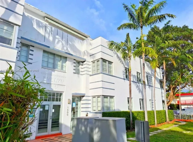 a front view of a building with a garden and plants