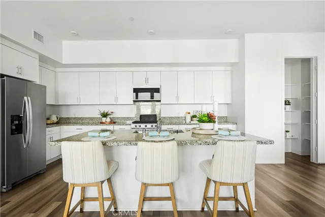 a kitchen with stainless steel appliances a dining table chairs and a refrigerator