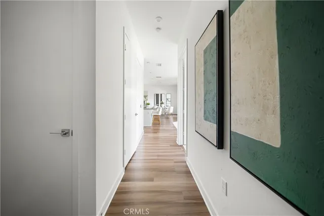 a view of a hallway with wooden floor and a bathroom