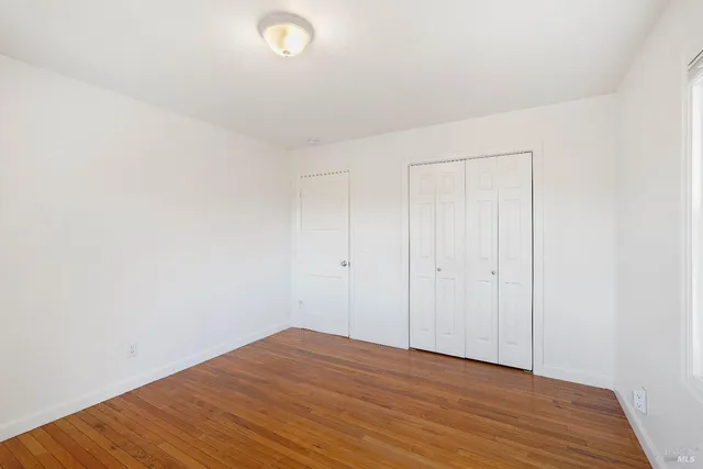 an empty room with wooden floor and window