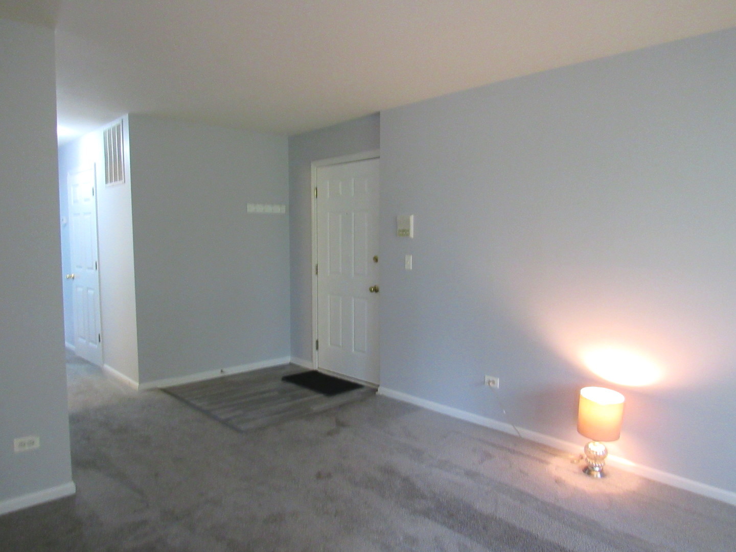 1202 North Red Oak Circle, Unit 2 Round Lake Beach, IL 60073 - Photo 2 of 18 an empty room with lamp and wooden floor