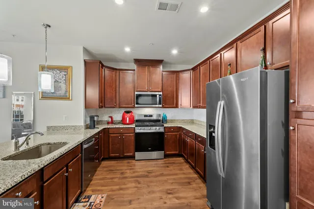 a kitchen with kitchen island granite countertop a sink refrigerator and cabinets