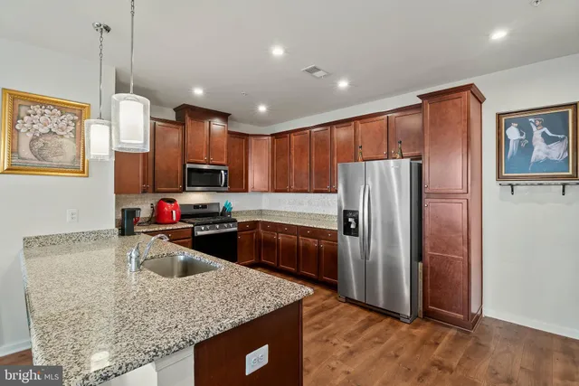 a kitchen with stainless steel appliances granite countertop a refrigerator a sink a stove a microwave and island