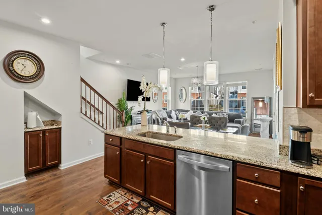a kitchen with stainless steel appliances granite countertop a sink a stove and a wooden floors