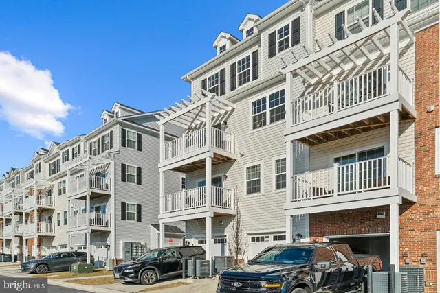 a front view of a building with lot of cars and trees