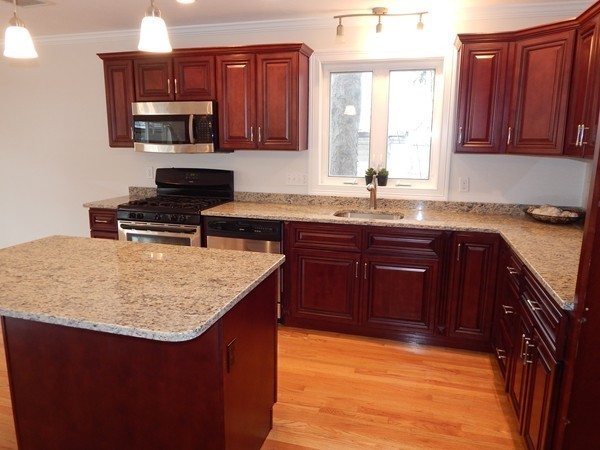 80 Locust Street Brockton, MA 02301 - Photo 10 of 20 a kitchen with a sink a stove a kitchen island and wooden cabinets