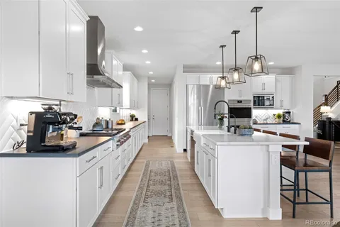 a kitchen with stainless steel appliances kitchen island granite countertop a table chairs and white cabinets