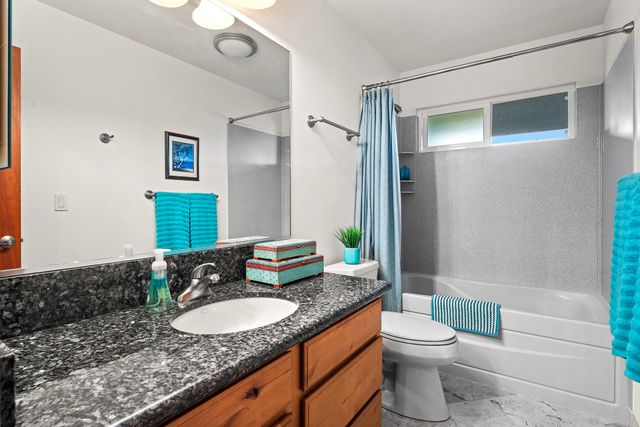 a bathroom with a granite countertop sink a toilet a mirror and shower
