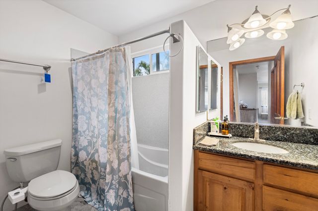 a bathroom with a granite countertop sink a toilet and a mirror