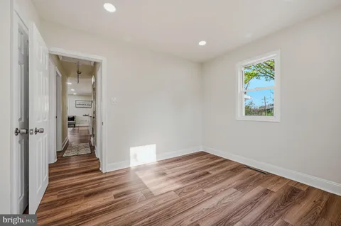 a view of a hallway with wooden floor and a bathroom