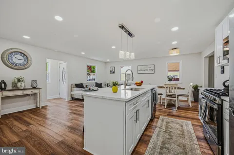 a kitchen that has a lot of cabinets a sink and a stove with wooden floor