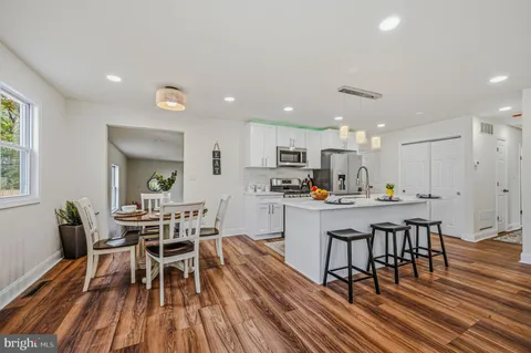 a kitchen with a dining table chairs wooden floor stainless steel appliances and window