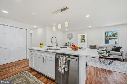 a kitchen with a sink dishwasher a dining table and chairs with wooden floor