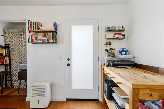 a utility room with fridge and wooden floor