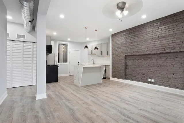 an empty room with wooden floor and kitchen view
