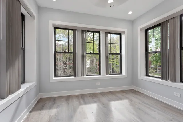 a view of an empty room with a window and wooden floor