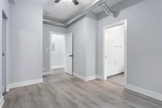 an empty room with wooden floor and a ceiling fan
