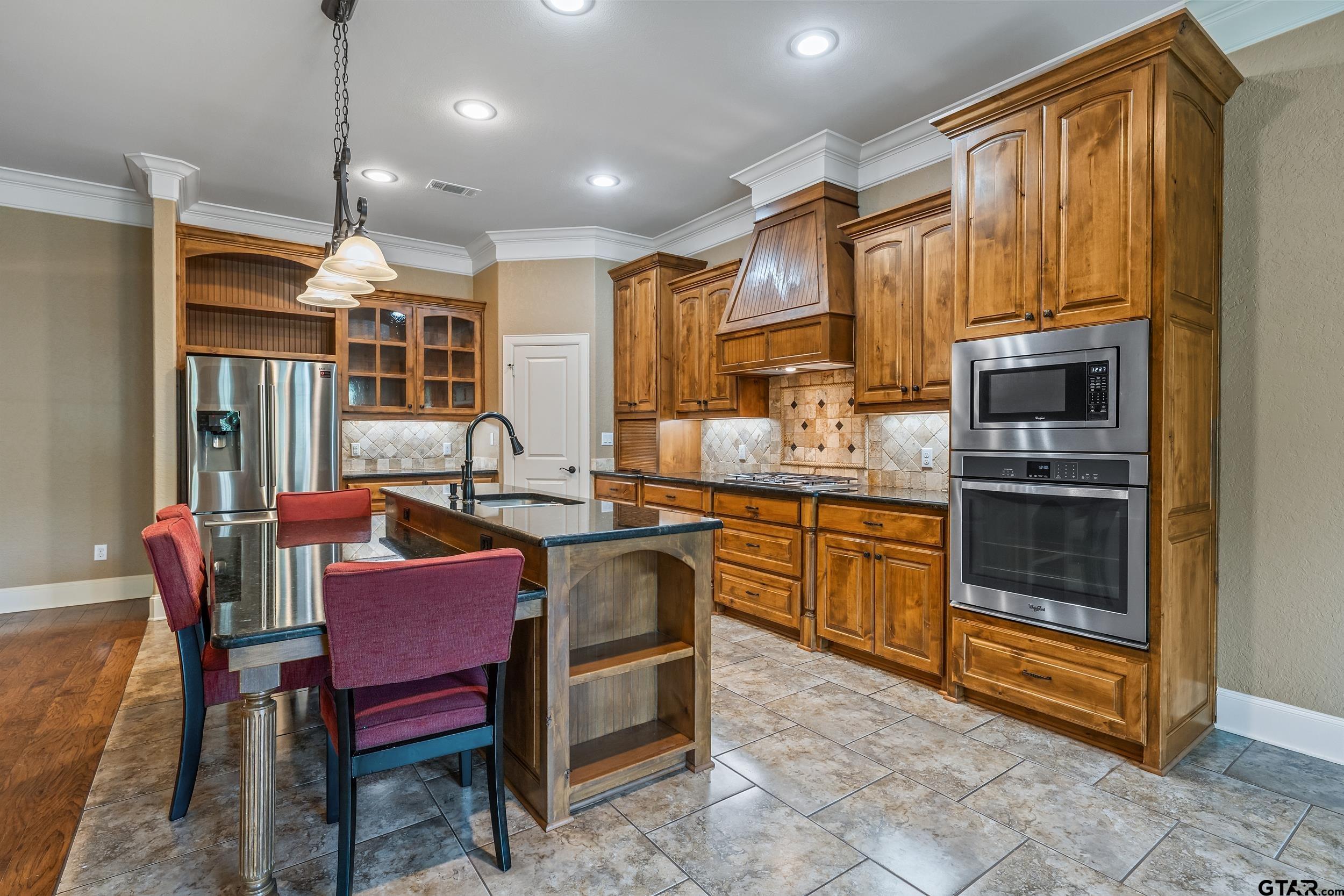 5524 Hollytree Drive Tyler, TX 75703 - Photo 11 of 27 a open kitchen with stainless steel appliances granite countertop a stove a sink dishwasher a dining table and chairs with wooden floor