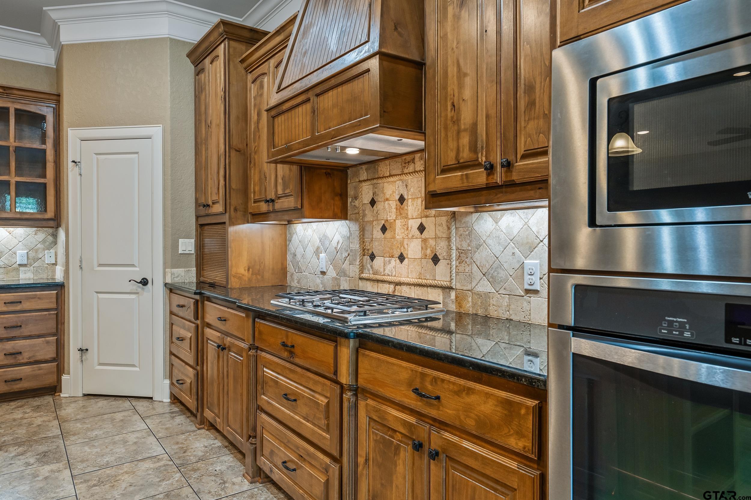 5524 Hollytree Drive Tyler, TX 75703 - Photo 12 of 27 a kitchen with stainless steel appliances granite countertop a stove and a microwave