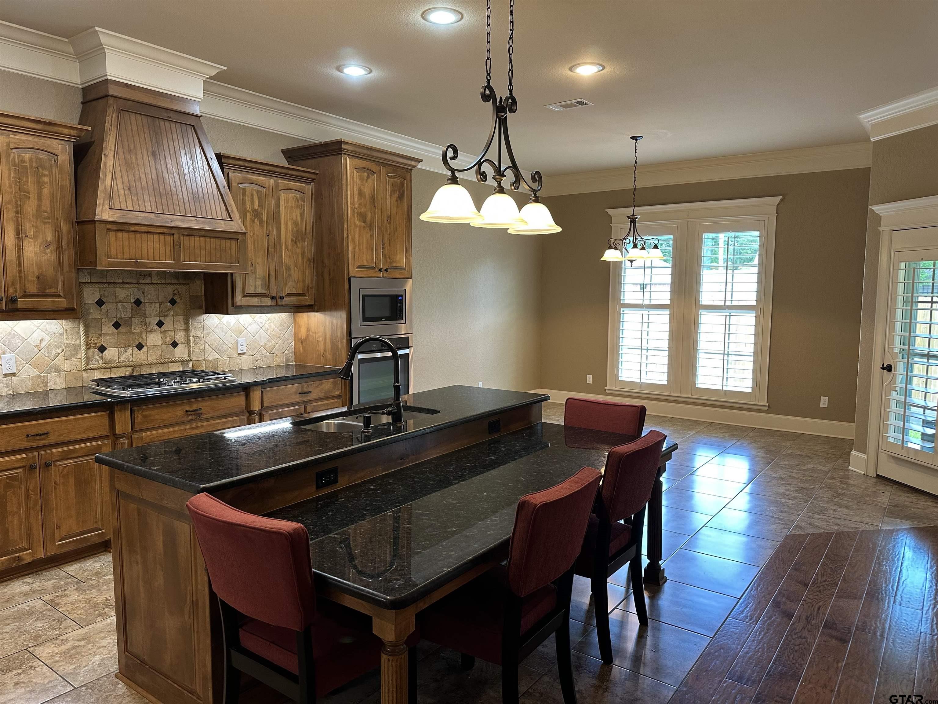 5524 Hollytree Drive Tyler, TX 75703 - Photo 10 of 27 a kitchen with a kitchen island hardwood floor sink stove dining table and chairs