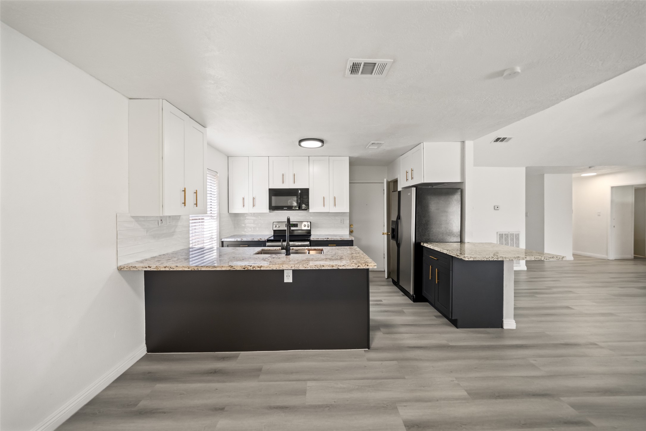 5726 Yorkgate Drive Spring, TX 77373 - Photo 11 of 20 a large kitchen with kitchen island a sink a stove a refrigerator and white cabinets