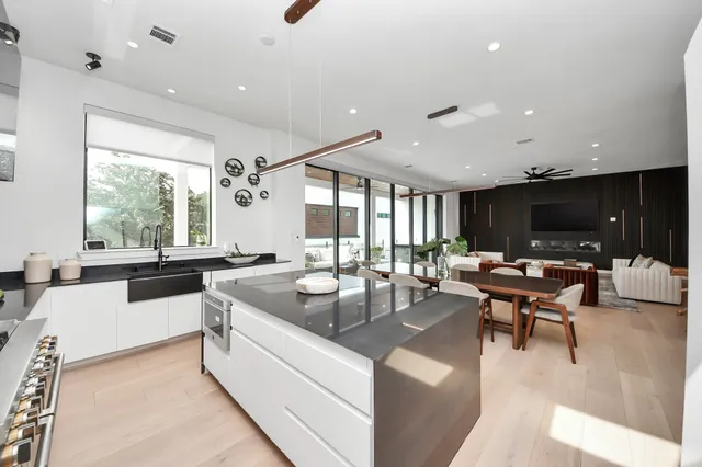 a living room with stainless steel appliances kitchen island granite countertop a sink and a large window