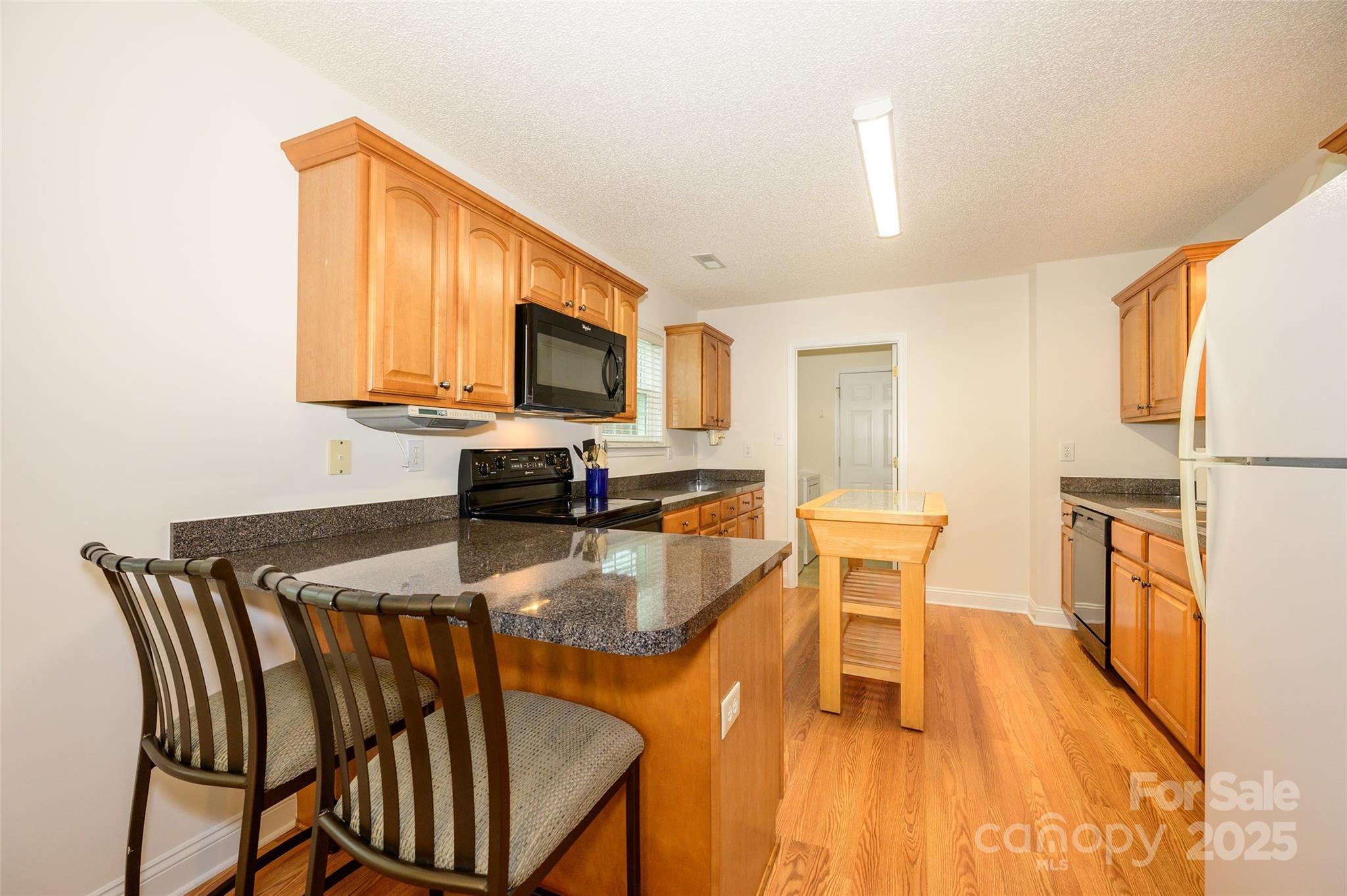12617 Hill Pine Road Midland, NC 28107 - Photo 11 of 42 a kitchen with stainless steel appliances granite countertop a stove top oven a sink a dining table and chairs with wooden floor