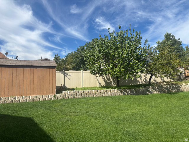 1324 West Raintree Drive, Unit 44 Price, UT 84501 - Photo 25 of 25 Spacious backyard featuring a manicured lawn, established trees, and a retaining wall