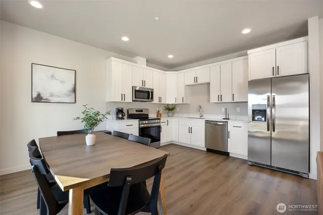 a kitchen with white cabinets stainless steel appliances and dining table