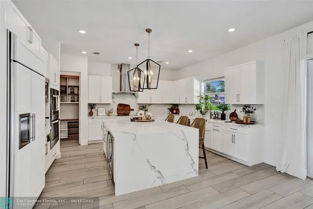 a large white kitchen with lots of counter space a sink and appliances