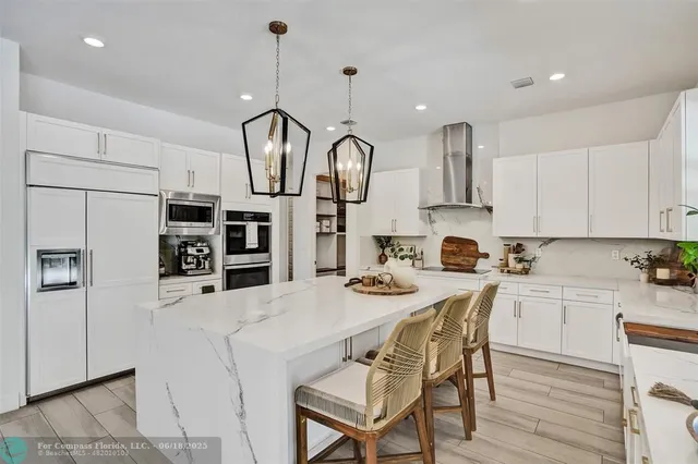 a kitchen with stainless steel appliances granite countertop a sink a stove a refrigerator cabinets and chairs