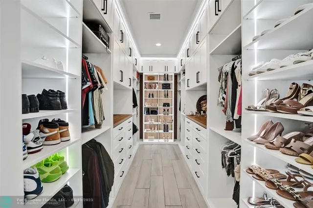 a view of a walk in closet with clothes and shoes