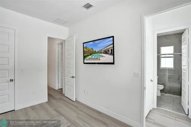 a view of a hallway with wooden floor and a bathroom