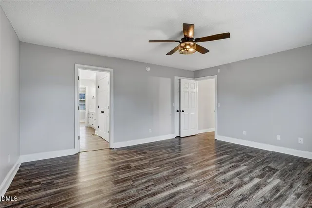 a view of an empty room with chandelier fan and wooden floor